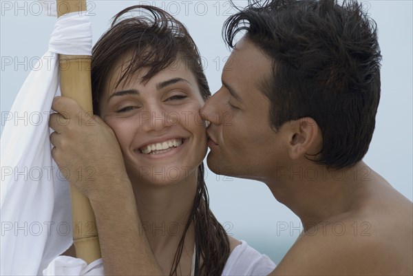 Hispanic man kissing girlfriend on cheek