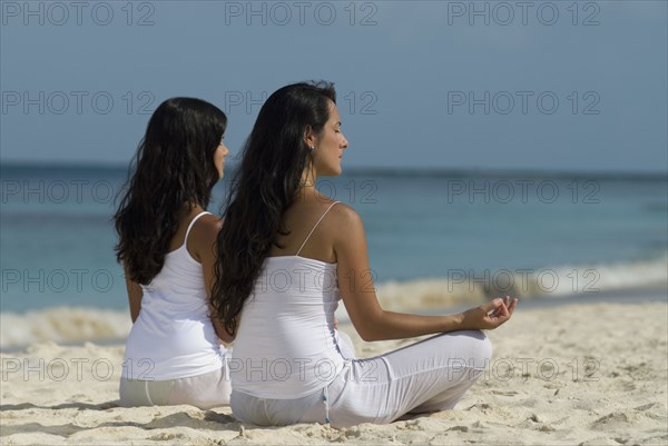 Hispanic women meditating at beach