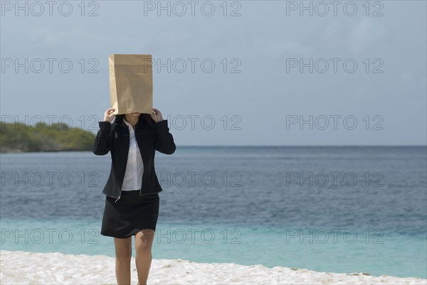 Hispanic businesswoman wearing bag over head