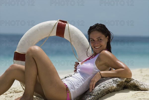 Young woman holding life preserver at beach