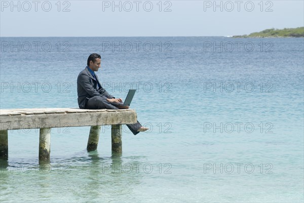 Hispanic businessman with laptop on dock