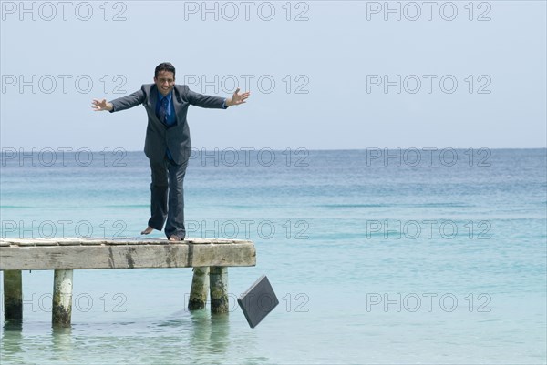 Hispanic businessman throwing laptop into water