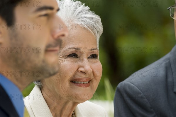 Senior Hispanic businesswoman next to businessmen