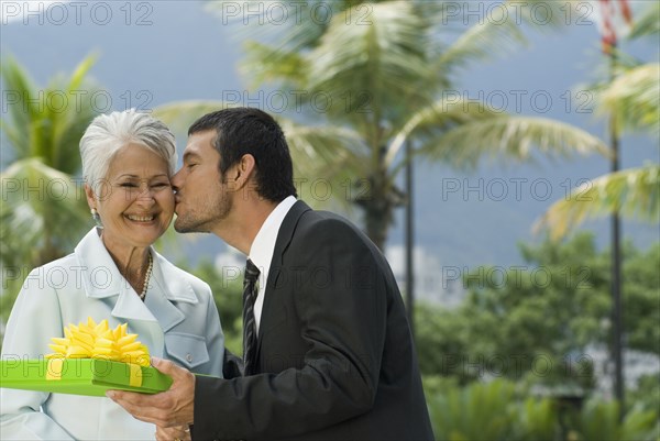 Hispanic man giving gift to mother