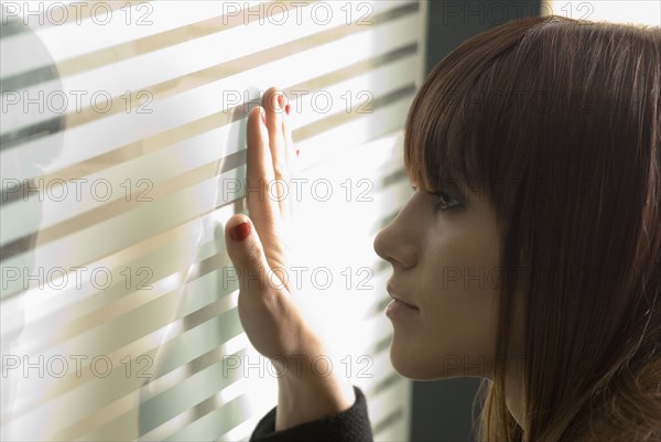 Young woman looking through frosted glass