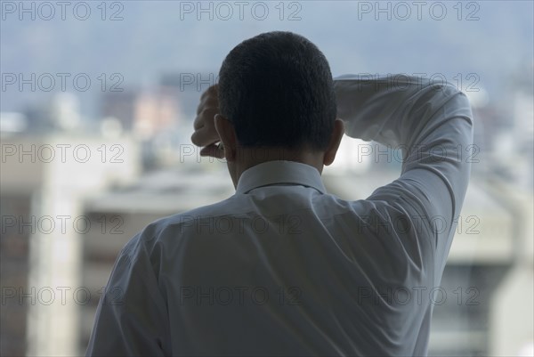 Hispanic businessman looking out window