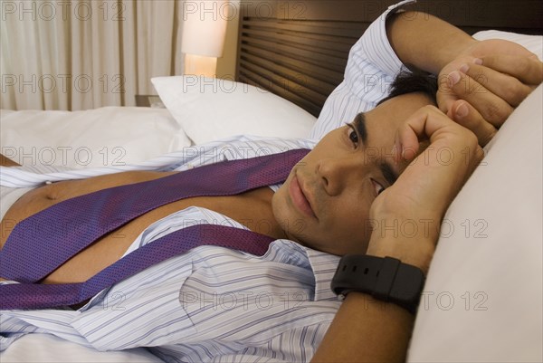 Hispanic businessman laying on bed