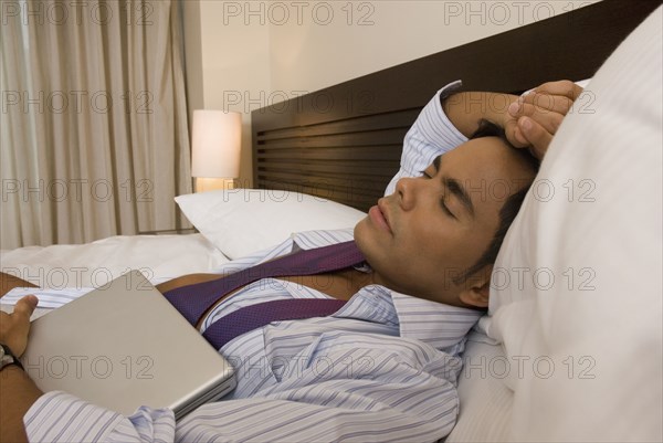 Hispanic businessman sleeping on bed