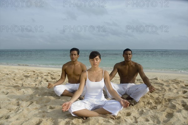 Multi-ethnic friends meditating on beach