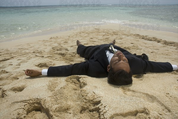 Hispanic businessman laying on beach