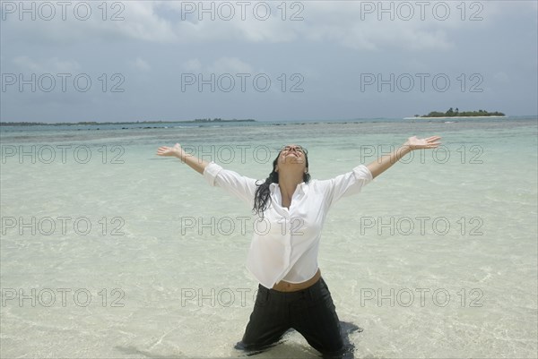 Hispanic businesswoman kneeling in water