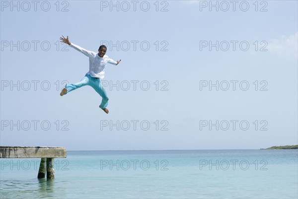 Hispanic man jumping off dock