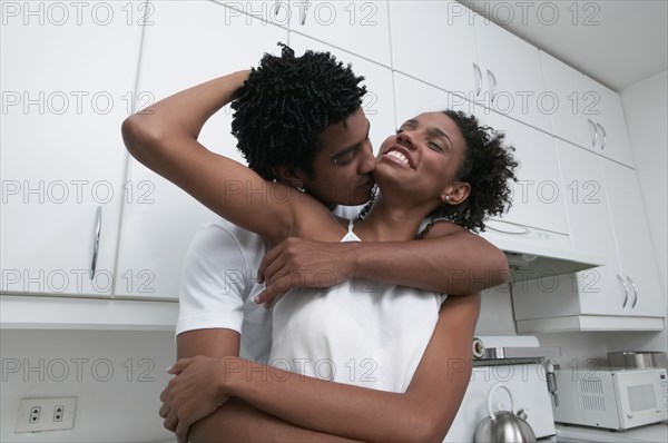 African couple hugging in kitchen