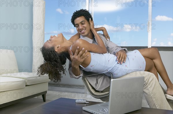 African couple hugging in chair