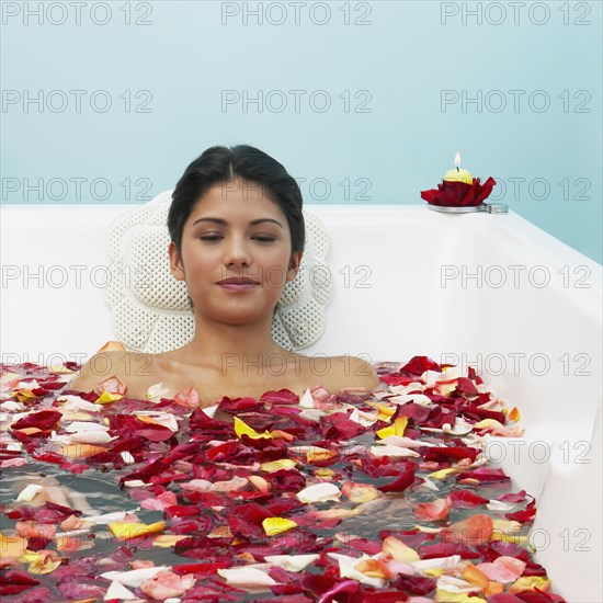 Hispanic woman in bathtub with flower petals