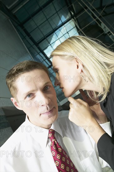 Businesswoman telling businessman a secret