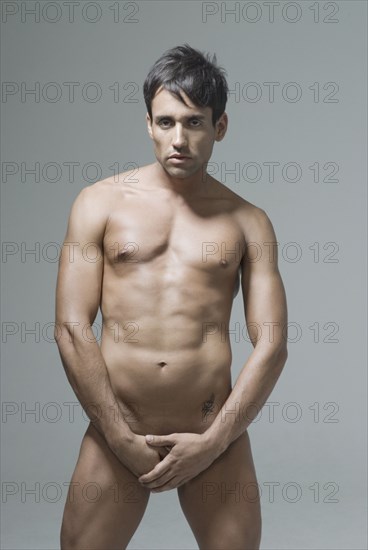 Nude Hispanic man covering his groin