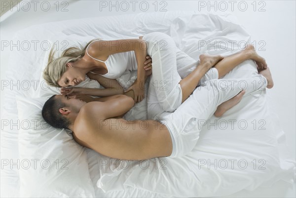 Smiling Hispanic couple laying in bed