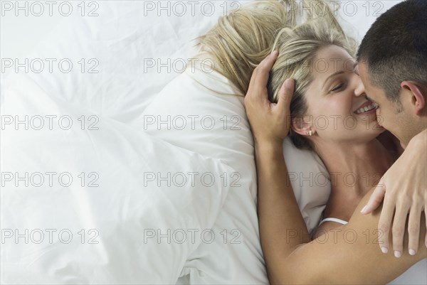 Smiling Hispanic couple laying in bed