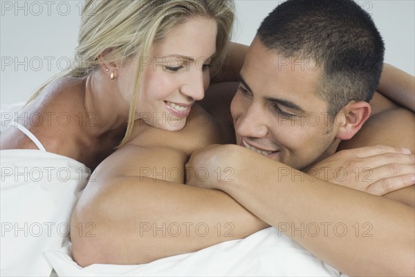 Smiling Hispanic couple laying in bed
