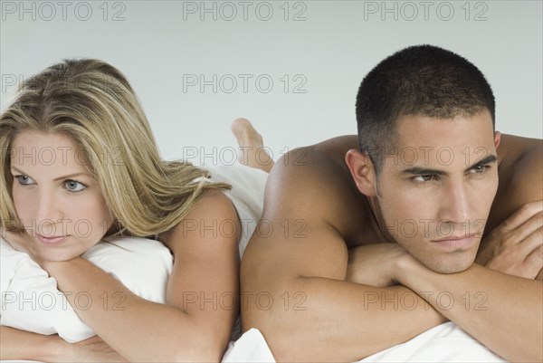 Angry Hispanic couple laying in bed