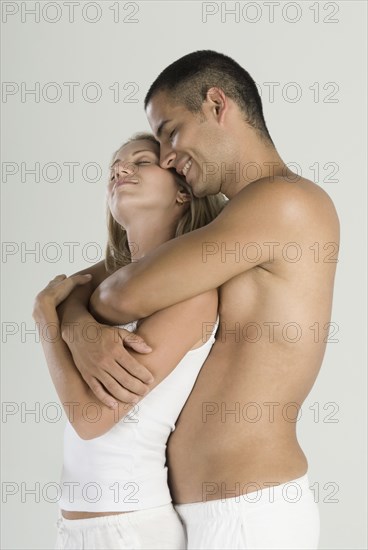 Hispanic couple hugging with eyes closed