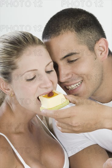 Hispanic man feeding girlfriend dessert