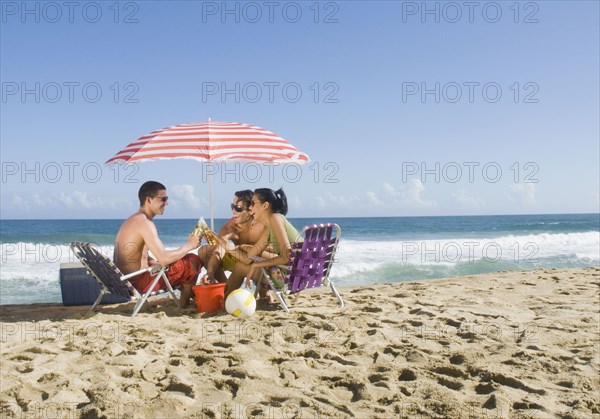 Hispanic friends relaxing at beach