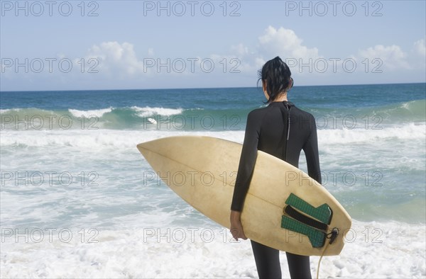 Hispanic woman at beach with surfboard