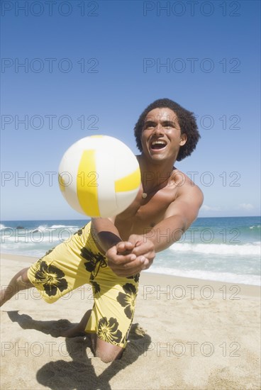 African man playing volleyball at beach