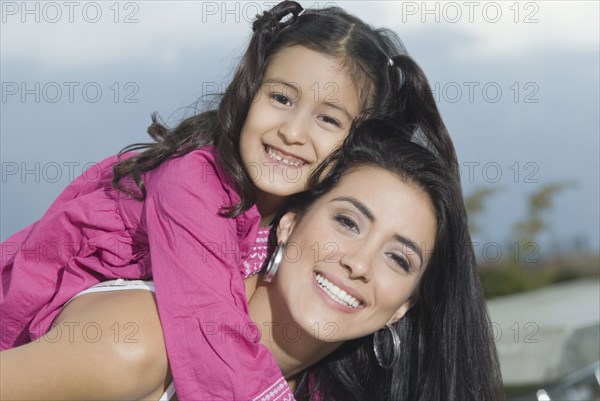 Hispanic mother giving daughter piggyback ride
