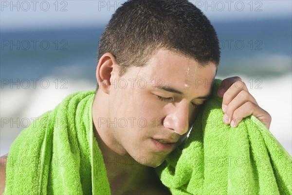 Sweating Hispanic man wiping face with towel