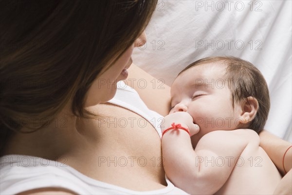 Hispanic woman watching baby sleep