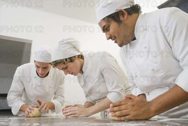 Bakers working with dough in bakery kitchen