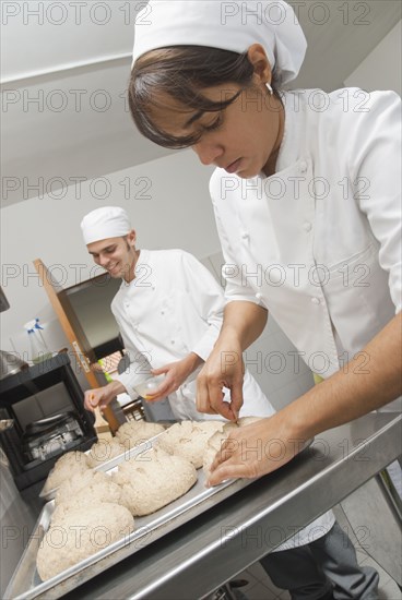 Bakers working with dough in bakery kitchen