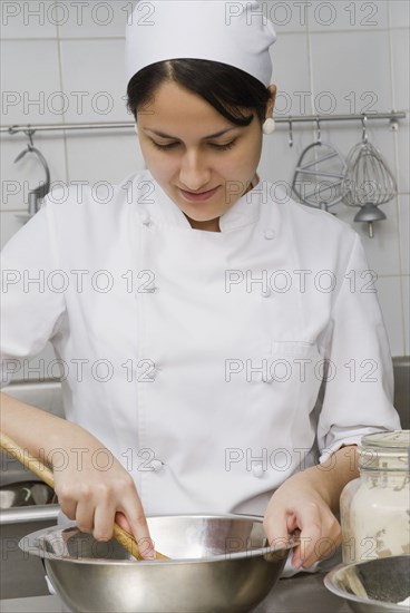 Baker stirring batter in bakery kitchen