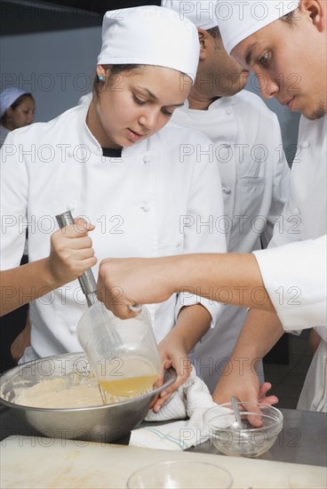 Bakers stirring batter in bakery kitchen