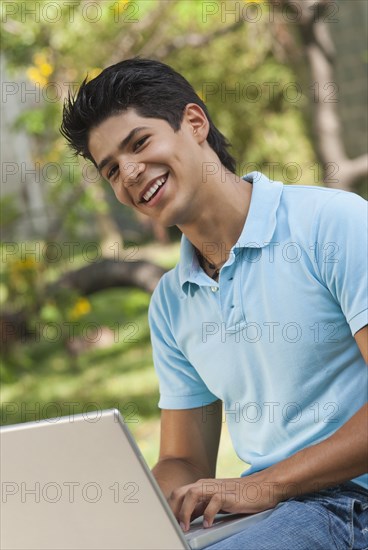 Hispanic man using laptop outdoors