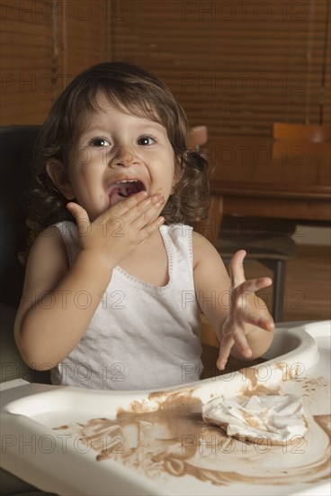 Hispanic baby in high chair licking hand