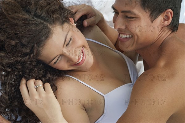 Laughing Hispanic couple laying in bed