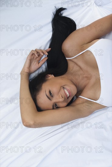 Smiling Hispanic woman laying in bed