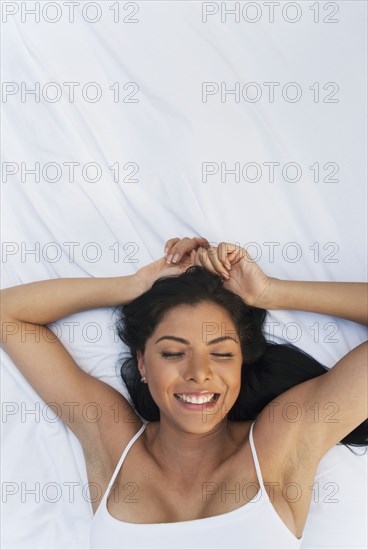 Smiling Hispanic woman laying in bed