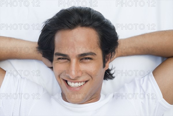 Smiling Hispanic man laying in bed