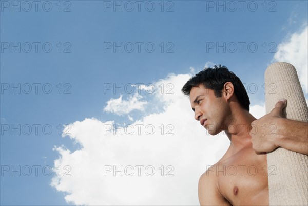 Serious Hispanic man carrying yoga mat