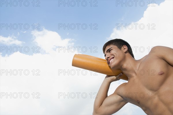 Smiling Hispanic man carrying yoga mat