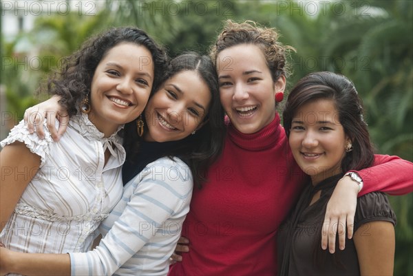 Smiling Hispanic friends hugging