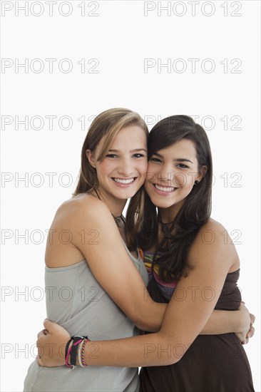 Smiling Hispanic sisters hugging