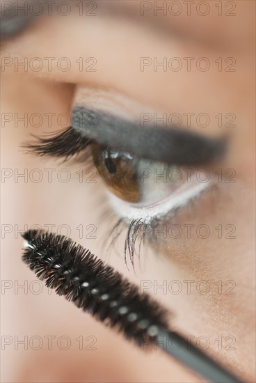 Caucasian woman putting on mascara