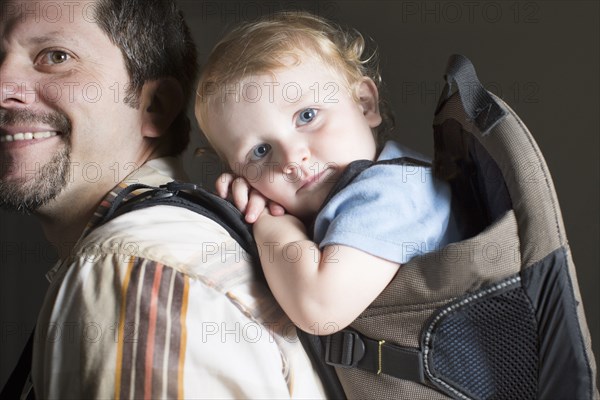 Caucasian father carrying son on back