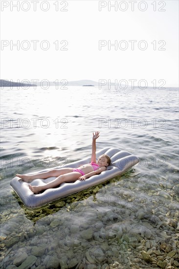 Caucasian girl floating on raft in lake